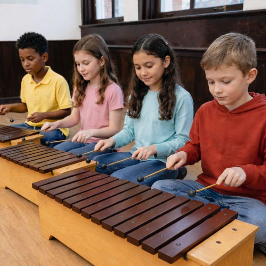 4 children playing Orff activities on xylophones in elementary music class.