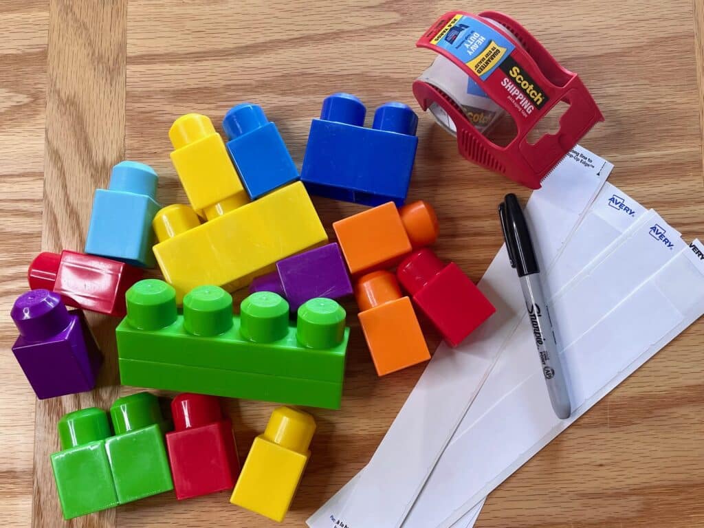 Duplo-style blocks, clear packing tape, address labels cut in half, black Sharpie marker